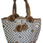 Bohemian crochet handbag, handmade by Wayuu artisans, tan and white weave, thick braided handles, playful pom-poms, and spacious design.