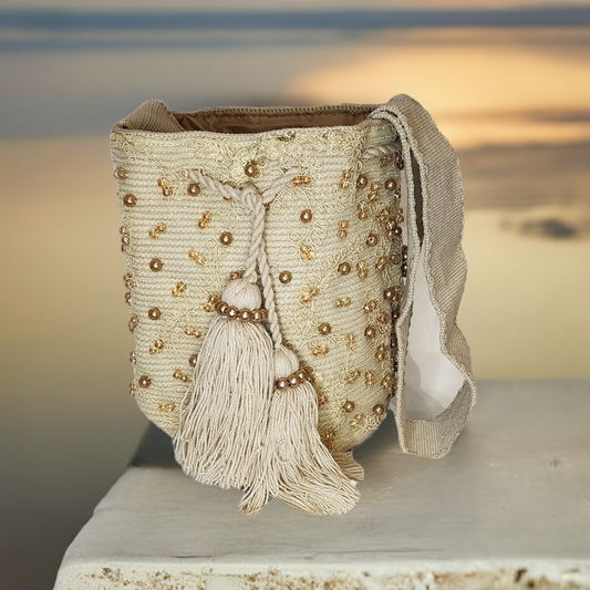 Handmade Wayuu crochet bag in cream with gold beadwork and soft tassels.