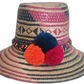 Handmade Wayuu straw hat with navy and fuchsia weave and pompoms in navy, orange, and fuchsia.

