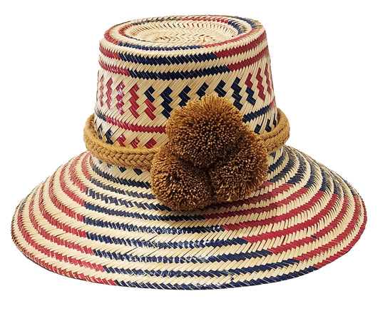 "Handcrafted colorful straw hat by Wayuu artisans using Iraca palm fibers, with adjustable weave and cultural pompoms."