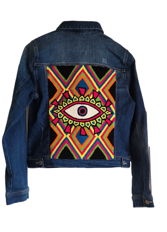 "Handcrafted denim jacket with colorful punch needle embroidery on the back, showcasing unique Wayuu-inspired patterns and fa