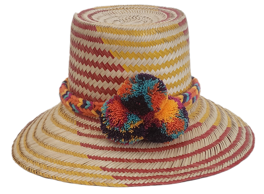 Colorful Wayuu straw hat with red and yellow chevron weave, multicolor braided band, and pom-poms.