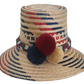Handwoven Wayuu straw hat with red, navy, and golden zigzag patterns and a braided band finished with tri-color pom-poms. A bold, artisan-crafted boho hat.