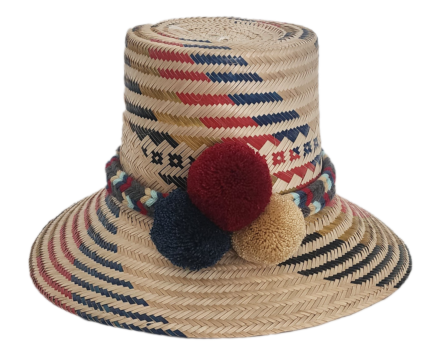Handwoven Wayuu straw hat with red, navy, and golden zigzag patterns and a braided band finished with tri-color pom-poms. A bold, artisan-crafted boho hat.