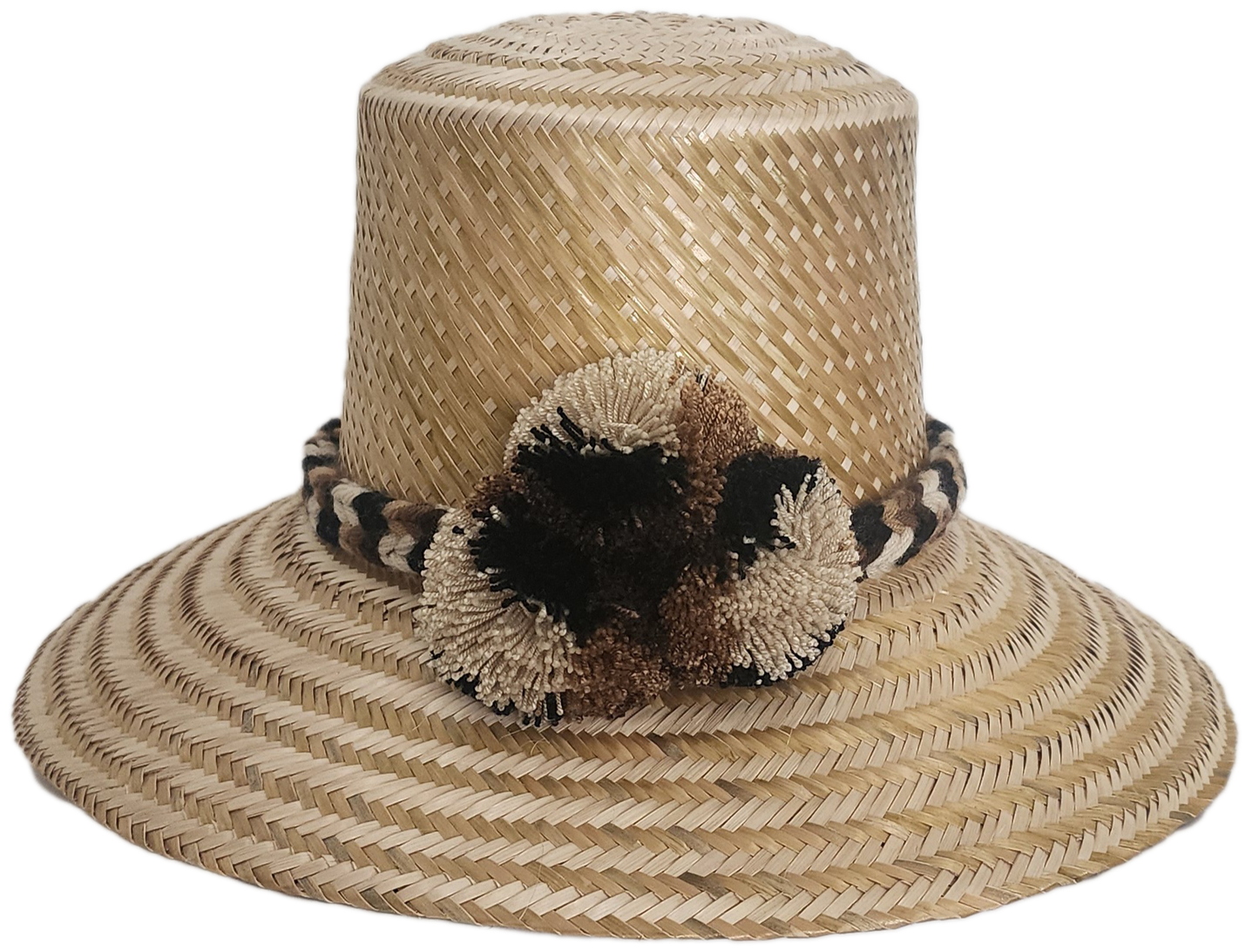 Handwoven Wayuu straw hat in a natural finish, featuring a braided band with earth-toned pom-poms in black, beige, and brown. A timeless boho accessory.