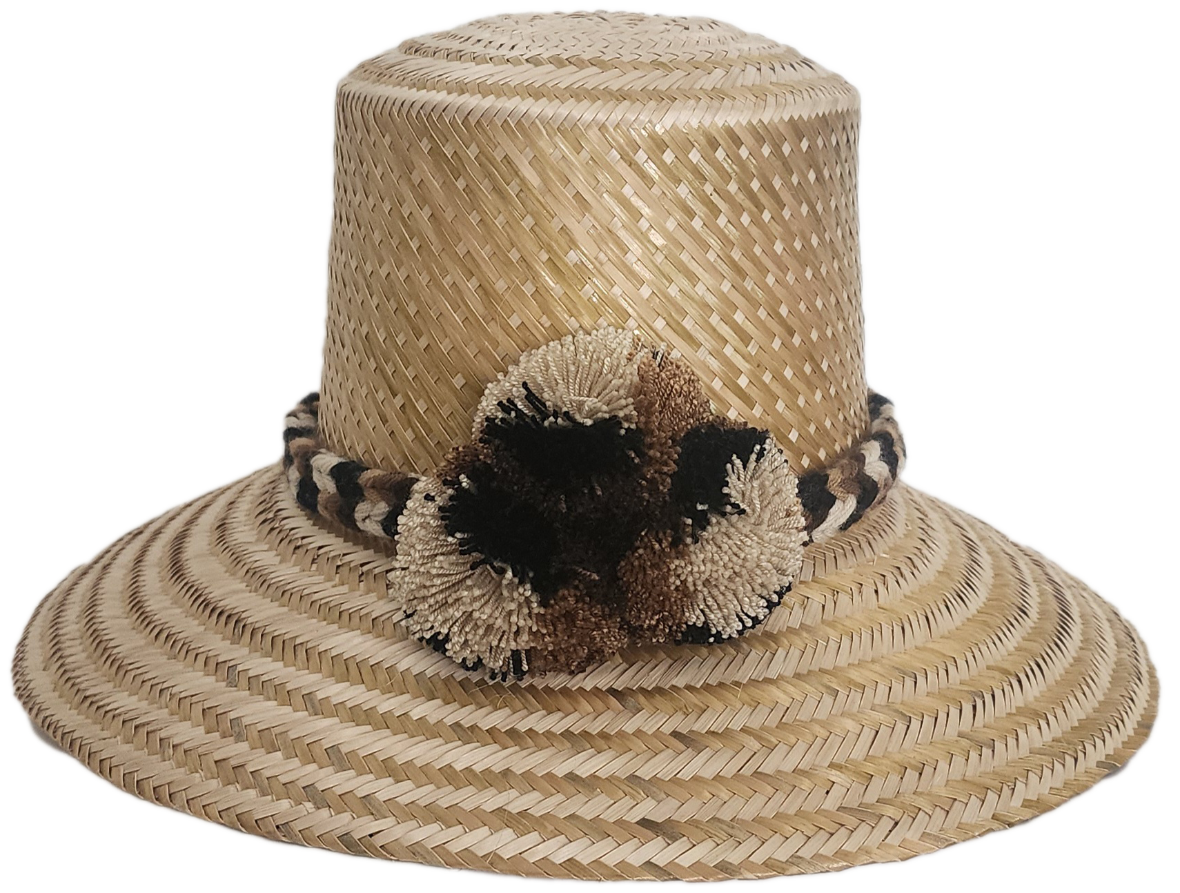 Handwoven Wayuu straw hat in a natural finish, featuring a braided band with earth-toned pom-poms in black, beige, and brown. A timeless boho accessory.