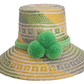 Handwoven Wayuu straw hat with green, yellow, and gray tribal patterns, wide brim, and bright green pom-pom band. A bold, bohemian summer accessory.
