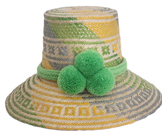 Handwoven Wayuu straw hat with green, yellow, and gray tribal patterns, wide brim, and bright green pom-pom band. A bold, bohemian summer accessory.