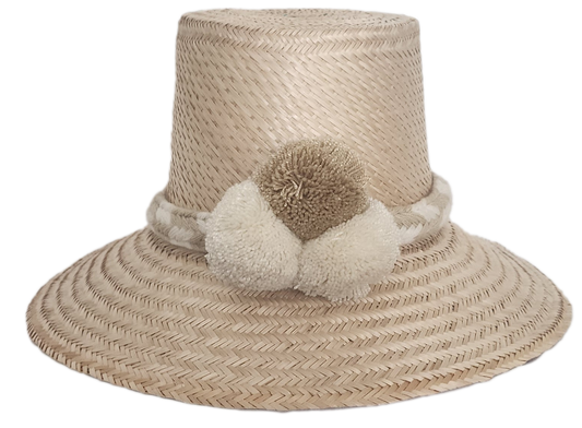 Handwoven Wayuu straw hat in soft beige tones, featuring a wide brim and braided band adorned with neutral cream and taupe pom-poms. Elegant boho style.