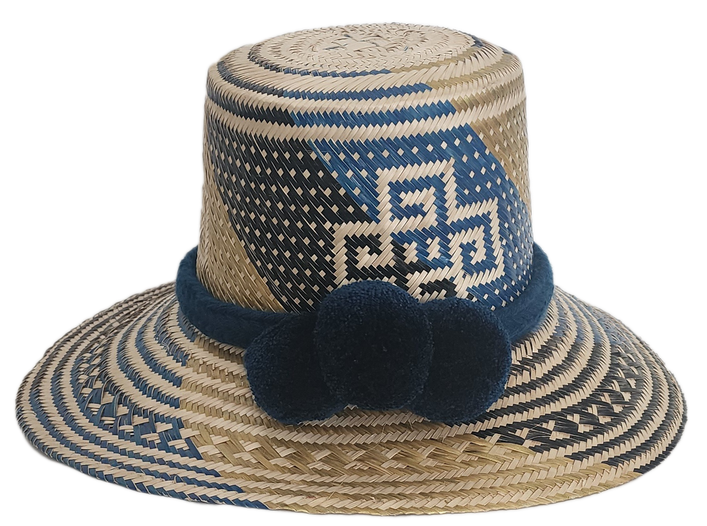 Artisan Wayuu straw hat with bold blue and cream geometric weaving, wide brim, and navy pom-pom band. A handcrafted boho accessory for standout summer style.