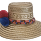 Boho-style handmade straw hat with vibrant pom-poms and woven band — crafted by Wayuu artisans for colorful summer fashion.