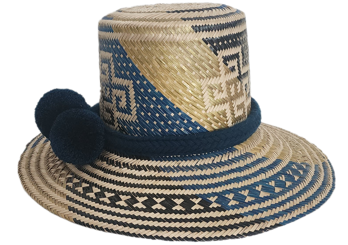 Artisan Wayuu straw hat with bold blue and cream geometric weaving, wide brim, and navy pom-pom band. A handcrafted boho accessory for standout summer style.