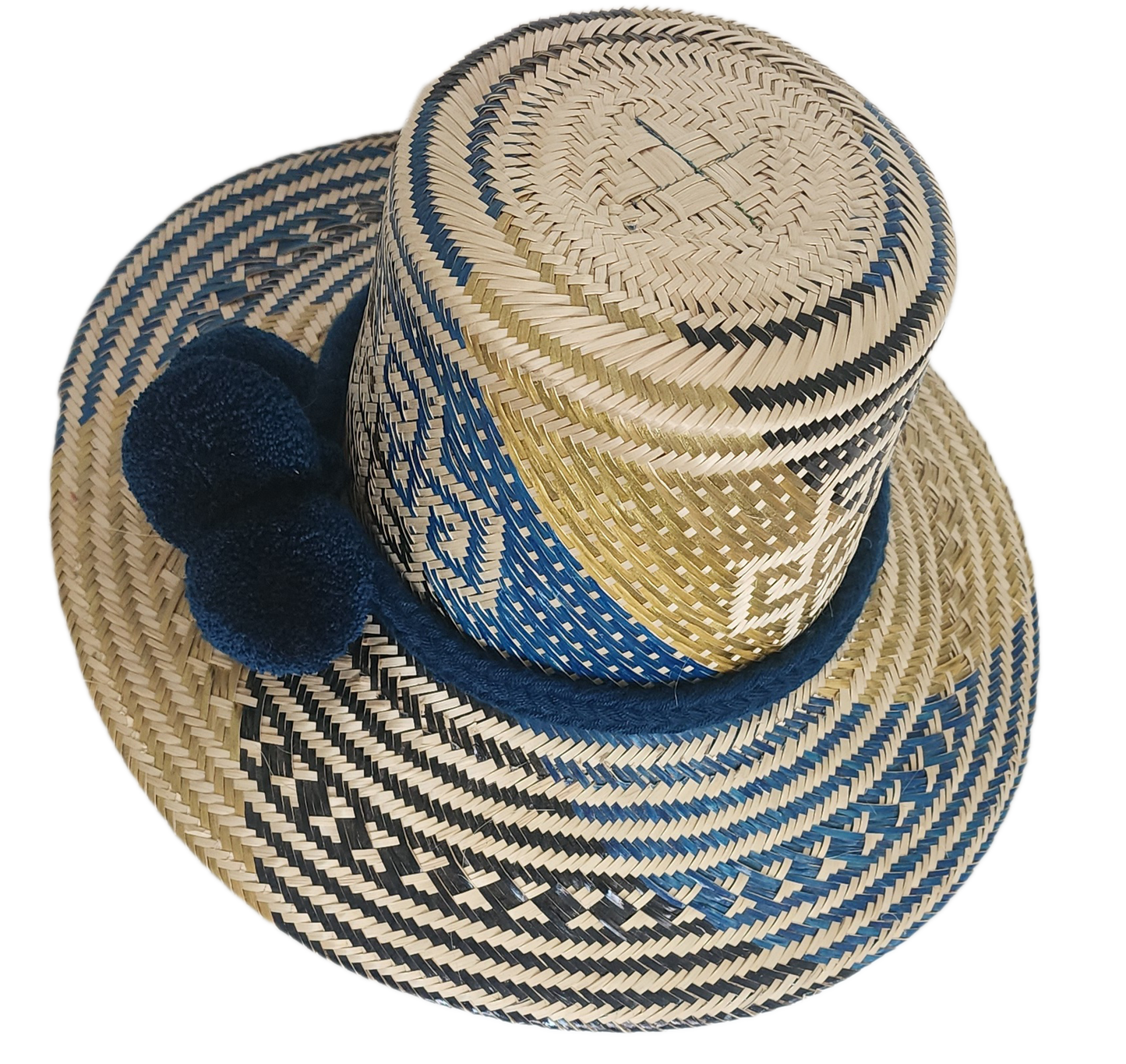 Artisan Wayuu straw hat with bold blue and cream geometric weaving, wide brim, and navy pom-pom band. A handcrafted boho accessory for standout summer style.