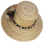 Handwoven Wayuu straw hat in a natural finish, featuring a braided band with earth-toned pom-poms in black, beige, and brown. A timeless boho accessory.