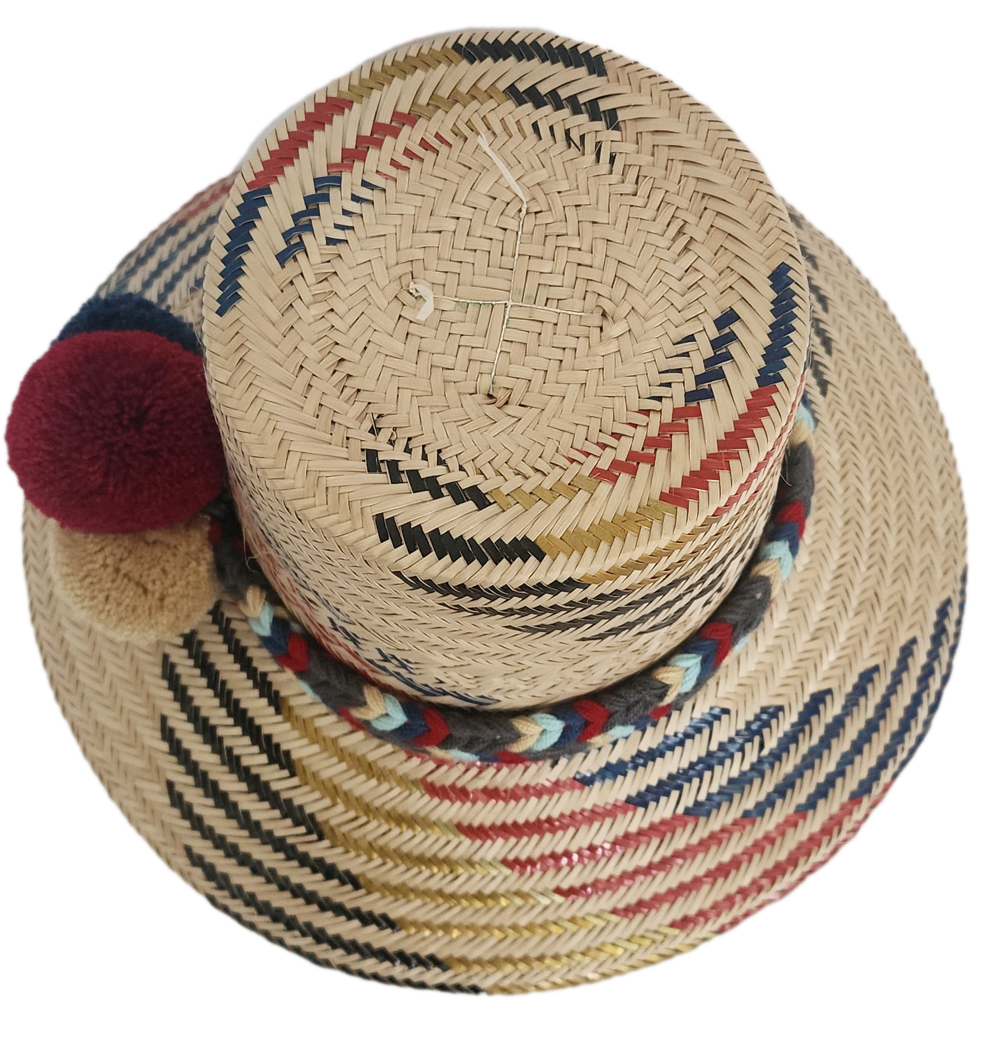 Handwoven Wayuu straw hat with red, navy, and golden zigzag patterns and a braided band finished with tri-color pom-poms. A bold, artisan-crafted boho hat.