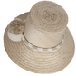 Handwoven Wayuu straw hat in soft beige tones, featuring a wide brim and braided band adorned with neutral cream and taupe pom-poms. Elegant boho style.