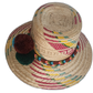 Bohemian straw hat crafted by Wayuu artisans with earth-toned patterns and artisan pompoms.