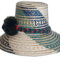 Colorful Wayuu hat with forest-toned straw weaving and vibrant handmade pompoms.