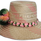 Handmade bohemian straw hat with colorful pompoms and geometric pink pattern.