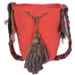 Handmade Wayuu mochila in coral pink with colorful tassel accents and braided shoulder strap — a vibrant, bohemian crochet bag.