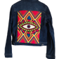 "Handmade denim jacket with colorful Wayuu-inspired punch needle embroidery on the back, showcasing unique bohemian style."