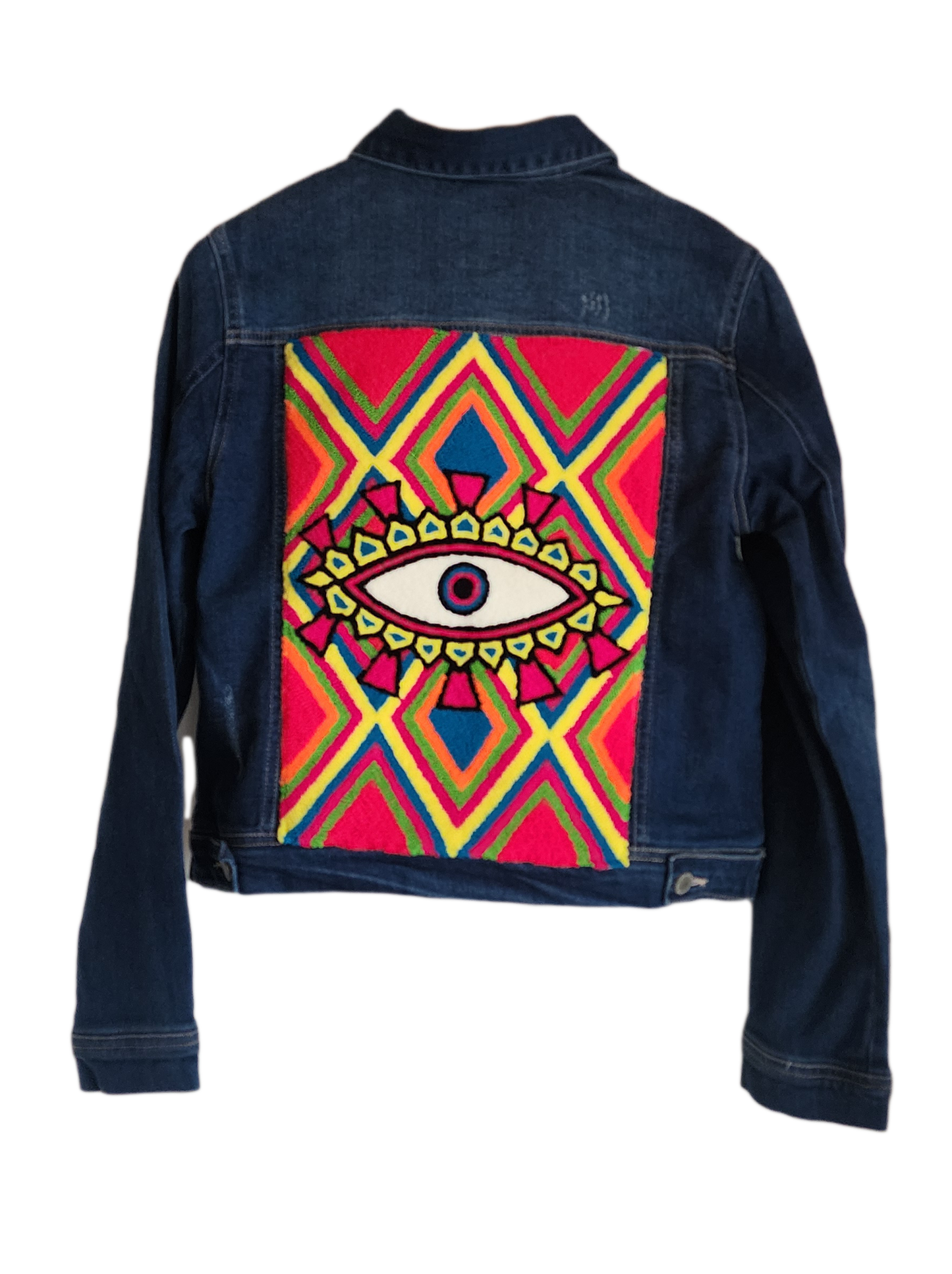 "Handmade denim jacket with colorful Wayuu-inspired punch needle embroidery on the back, showcasing unique bohemian style."