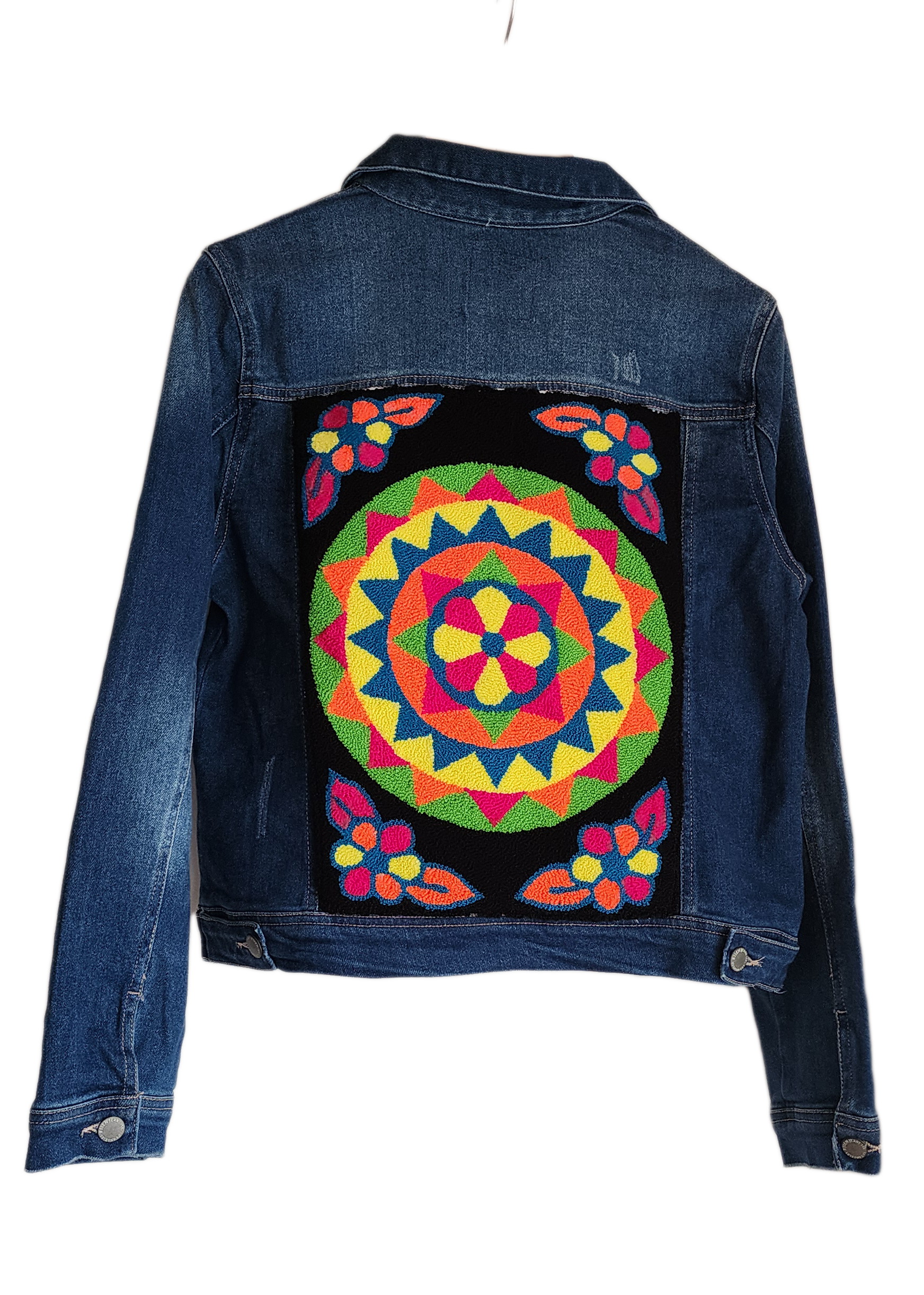 "Handmade denim jacket with colorful Wayuu-inspired punch needle embroidery on the back, showcasing unique artisan craftsmans