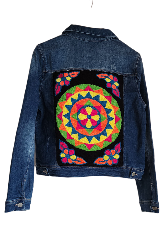 "Handmade denim jacket with colorful Wayuu-inspired punch needle embroidery on the back, showcasing unique artisan craftsmans