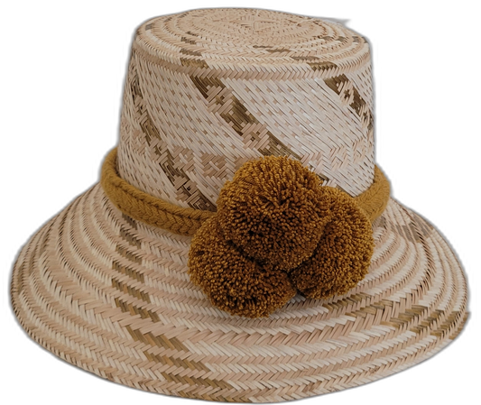 Handmade Wayuu straw hat in light natural tones with golden-brown pompoms.

