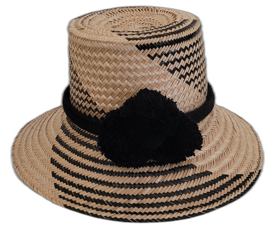 Handmade Wayuu black-and-natural straw hat with elegant black pompoms.