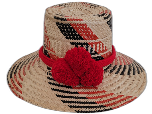 Handmade Wayuu straw hat with black, red, and natural weave, plus bold red pompoms.

