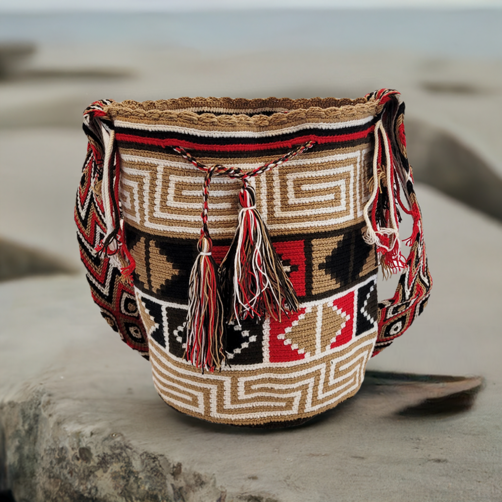 Handmade Wayuu crochet bag in black, red, tan, and white with layered geometric patterns, oversized red, black, and white tassels, artisan crossbody.