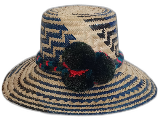 Handmade Wayuu straw hat with navy and black weave and dark green and red pompoms.Boho Wayuu hat featuring zigzag designs and handcrafted pompoms