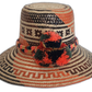 Handmade Wayuu straw hat with red, black, and green pompoms and tribal weave.