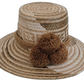 Handmade Wayuu straw hat with earthy brown tones and matching brown pompoms.

