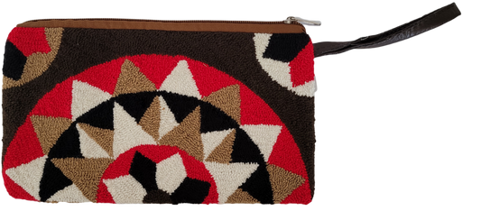 Handmade Wayuu punch needle clutch featuring earth-tone shades of red, black, cream, and brown in a bold geometric sunburst design. Boho chic, artisan-crafted.