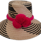 Handmade Wayuu straw hat with black and natural patterns, accented with hot pink pompoms.

