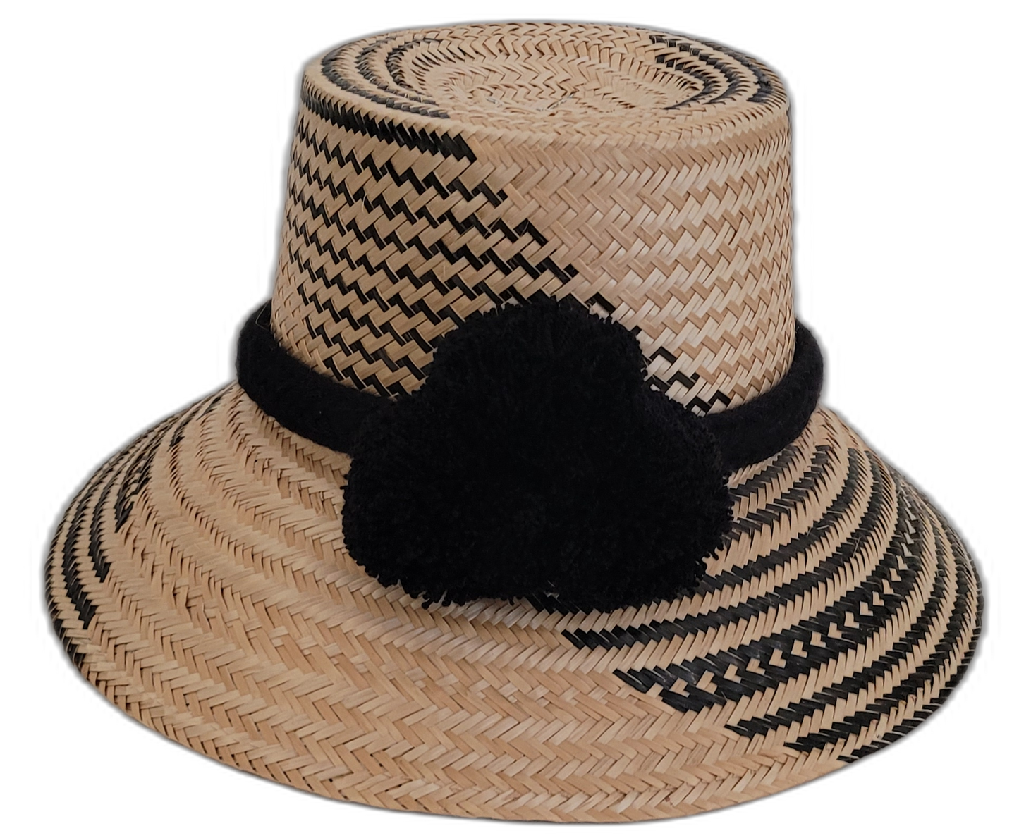 Handmade Wayuu straw hat with subtle black patterns and black pompoms.

