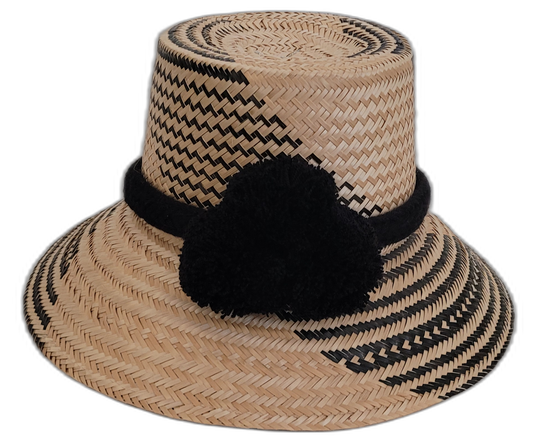 Handmade Wayuu straw hat with subtle black patterns and black pompoms.

