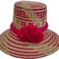 Handmade Wayuu straw hat with bold red patterns and vibrant red pompoms.

