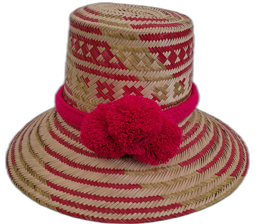 Handmade Wayuu straw hat with bold red patterns and vibrant red pompoms.

