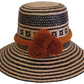Handmade Wayuu straw hat with black geometric patterns and bold burnt orange pompoms — artisan boho accessory with cultural flair.