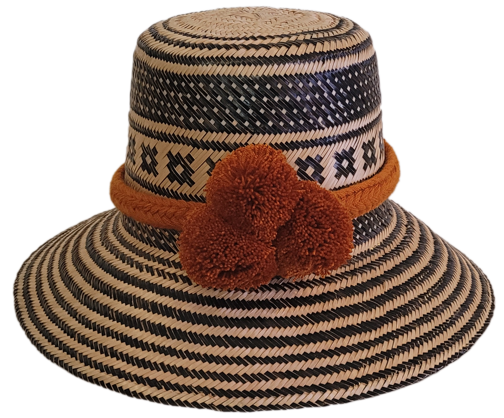 Handmade Wayuu straw hat with black geometric patterns and bold burnt orange pompoms — artisan boho accessory with cultural flair.