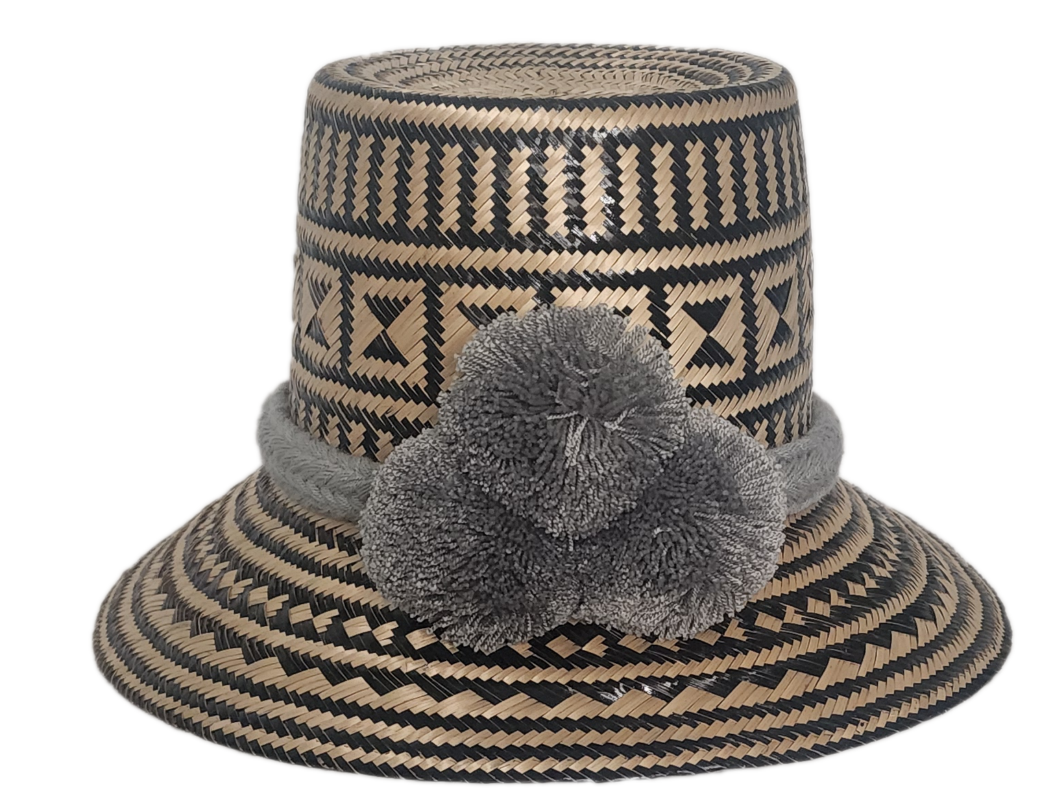 Handmade Wayuu straw hat with intricate black and natural geometric patterns, featuring a soft grey braided band and matching grey pom-poms.
