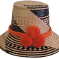 Handmade Wayuu straw hat in natural and black tones, featuring bold orange pompoms and tribal patterns — boho artisan piece for standout style.

