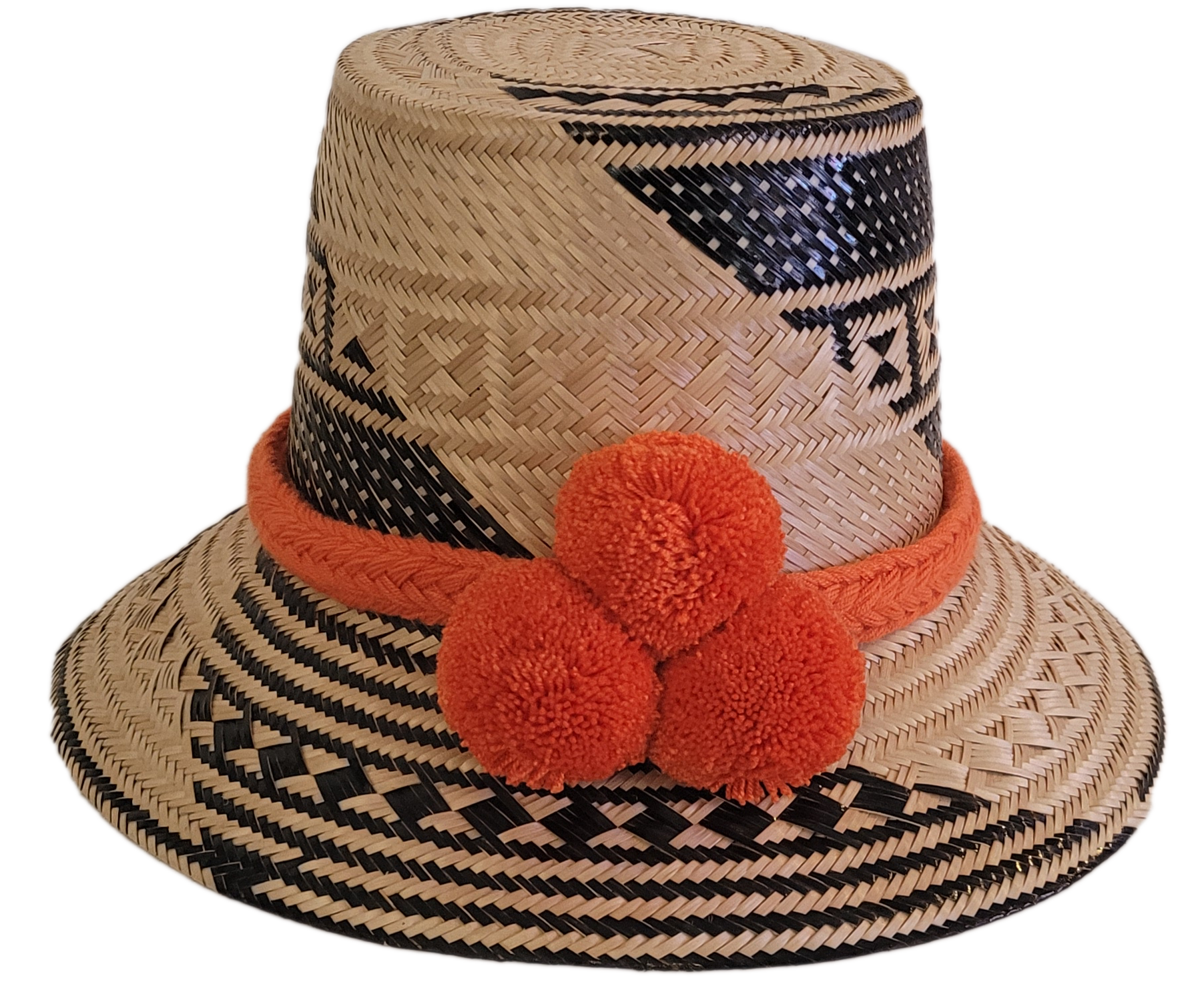 Handmade Wayuu straw hat in natural and black tones, featuring bold orange pompoms and tribal patterns — boho artisan piece for standout style.

