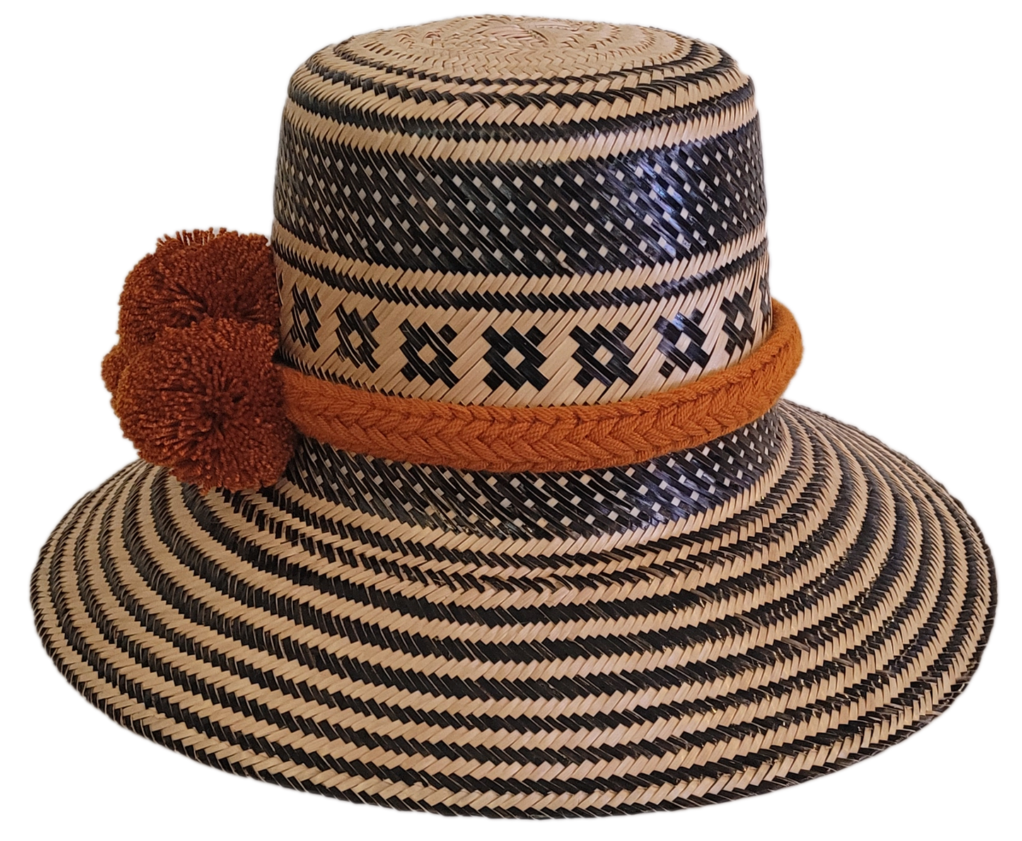 Boho-style Wayuu hat, handwoven from Iraca palm in black and natural tones, featuring a wide brim and rustic orange pom-poms for a unique finish.