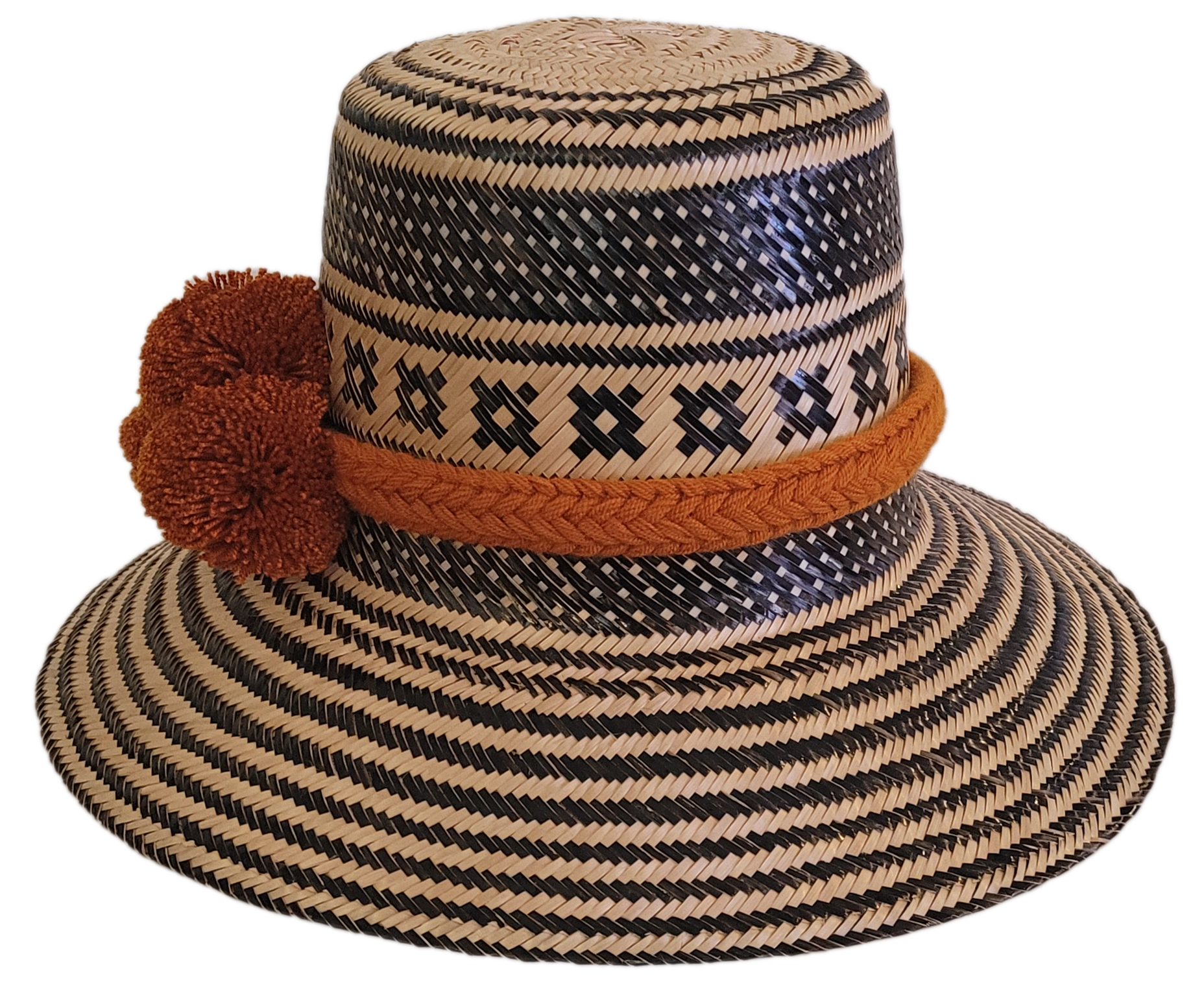 Boho-style Wayuu hat, handwoven from Iraca palm in black and natural tones, featuring a wide brim and rustic orange pom-poms for a unique finish.
