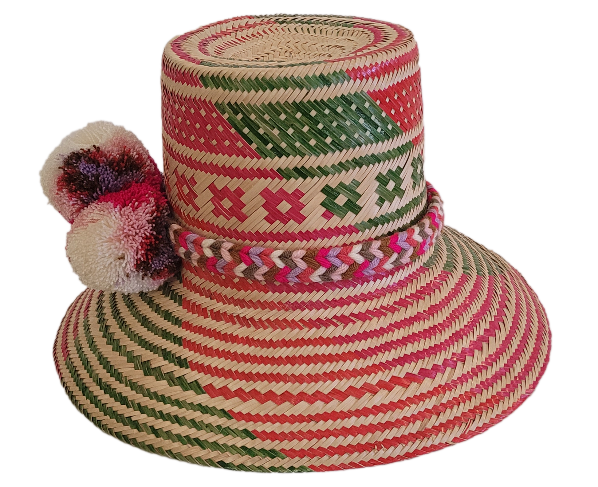 Boho chic Wayuu hat, handwoven from Iraca palm with vibrant red and green patterns and decorative cream and pink pompoms — perfect for summer style.