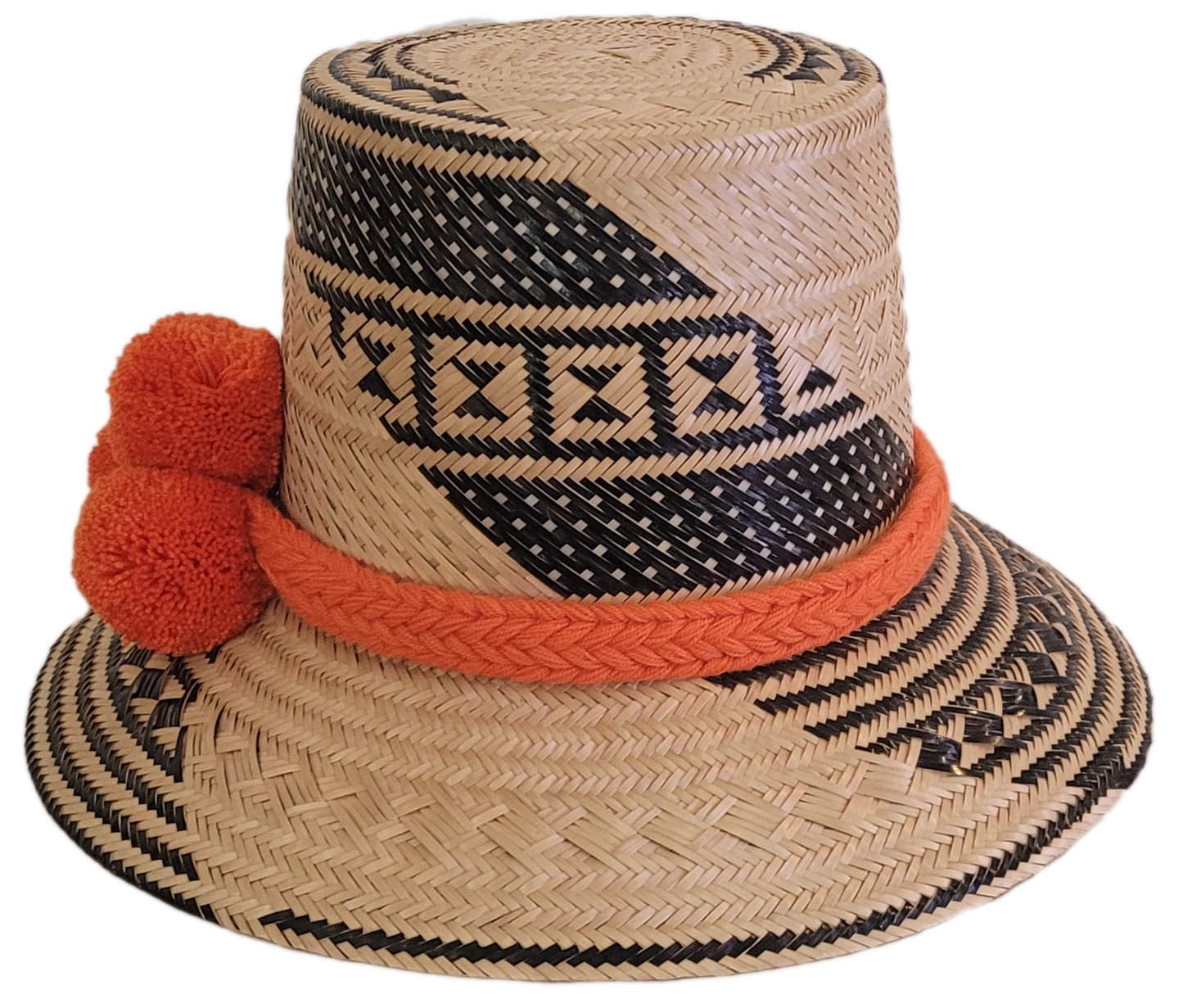 Bohemian-style artisan Wayuu hat with natural weave, black geometric accents, and vivid orange pom-poms — handcrafted for vibrant boho looks.